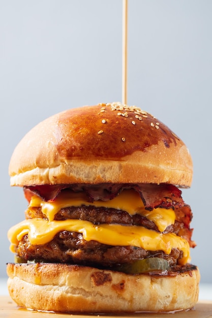 Photo burger double côtelette double fromage cheddar bacon oignons frits cornichons