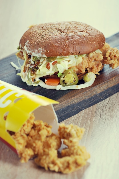 Burger avec du pain noir sur une planche de bois