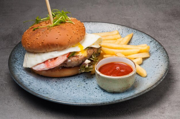 Burger avec escalope de poulet et oeuf avec frites et ketchup