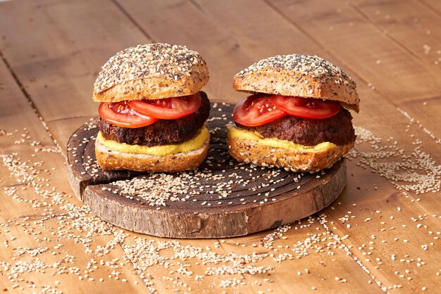 Burger fait maison avec tomates et moutarde sur la table en bois.