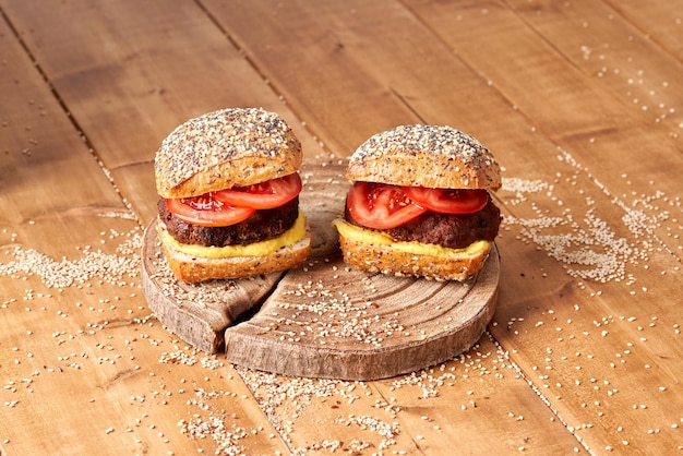 Burger fait maison avec tomates et moutarde sur la table en bois.