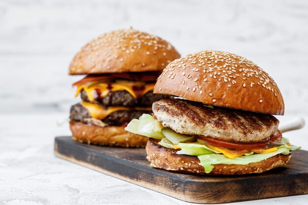 Burger fraîchement cuit sur planche de bois sur fond clair