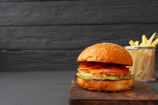 Burger frais et frites sur fond de bois noir, vue de face