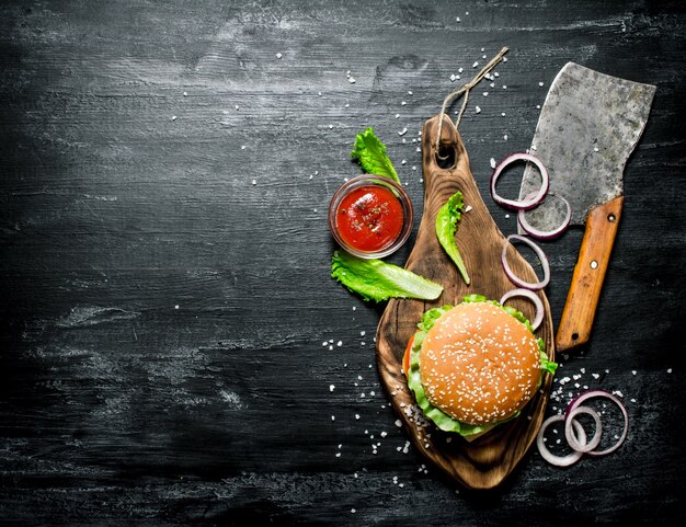 Le Burger et les ingrédients frais sur l'ancien plateau. Sur un tableau noir. Vue de dessus.