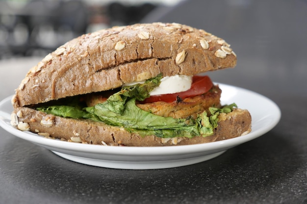 Un burger de légumes avec de la laitue et de la tomate sur une assiette sur la table