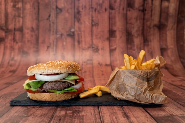 Burger à la main avec frites sur table en bois