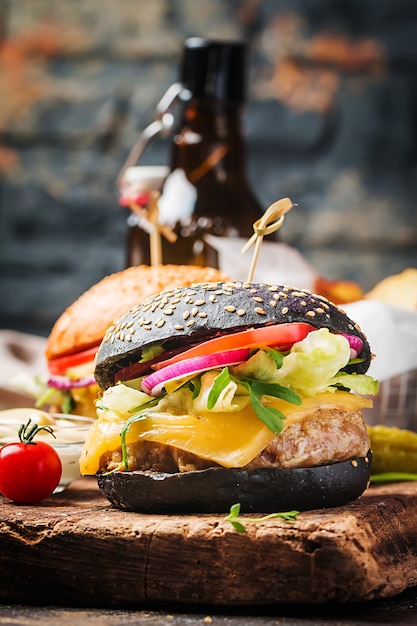 Burger noir de boeuf classique grillé savoureux avec laitue et sauce mayonnaise sur une table en bois rustique, avec copie espace