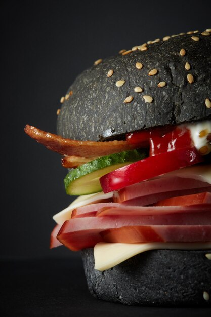 Burger noir gastronomique avec sauce épicée sur surface noire