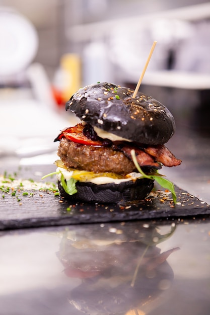 Burger noir sur une planche à découper en pierre dans un restaurant de cuisine