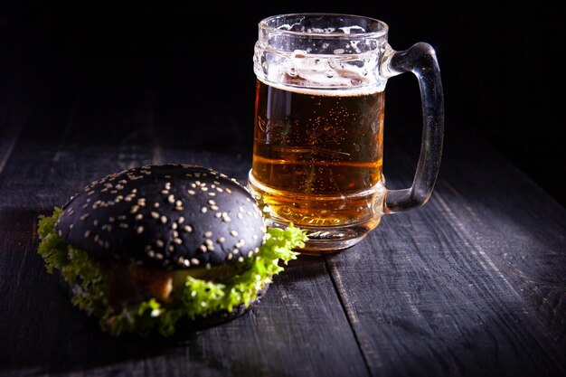 Burger noir et verre de bière isolé sur fond noir. mise au point douce. mise au point sélective.