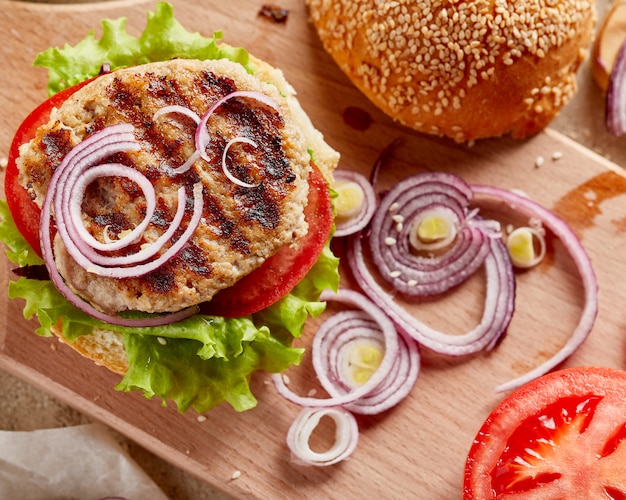 Burger sur planche de bois avec oignons et tomates