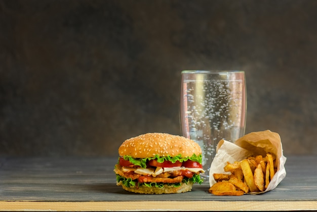 Burger sur une planche en bois rustique et une boisson sucrée aromatisée dans un verre