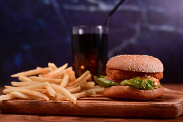 Burger de poisson avec pommes de terre frites sur planche de service en bois