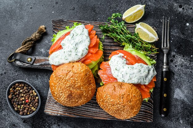 Burger de poisson avec saumon salé, avocat, sauce moutarde, concombre et salade Iceberg. vue de dessus.