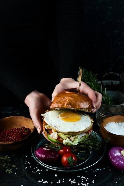 Burger de poulet frais et savoureux sur table en bois Dans les mains Sur fond noir