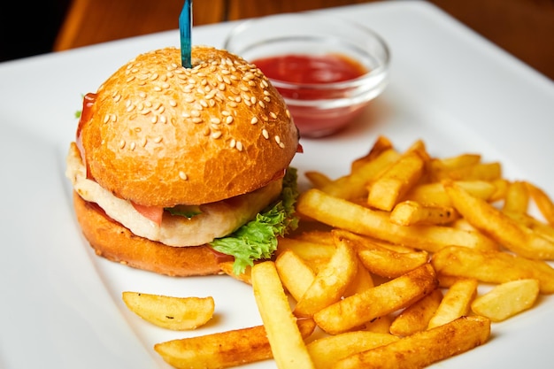 Burger de poulet et frites sur une plaque blanche