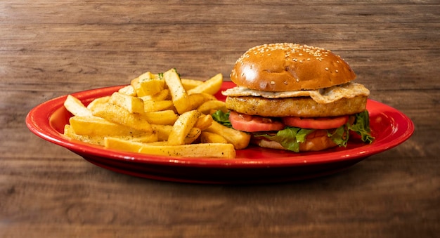 burger de poulet avec œuf frit, tomate, laitue et frites.