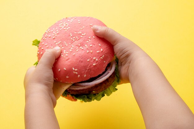 Burger rose dans les mains de l'enfant