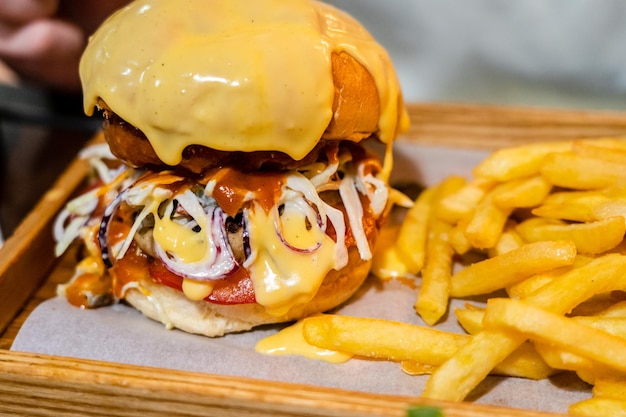 Burger savoureux et frites sur un bureau en bois