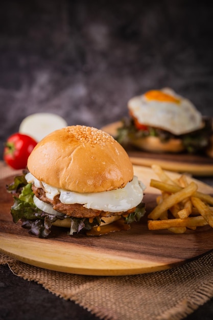 Burger servi avec des frites sur une assiette en bois