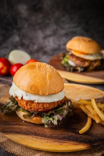 Burger servi avec des frites sur une assiette en bois