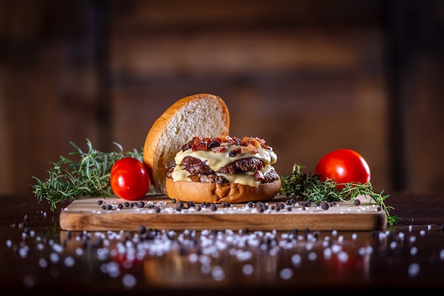 Burger de smash de boeuf artisanal avec fromage, bacon et sauce sur fond de bois