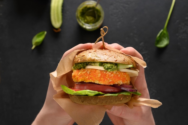 Burger végétalien de petits pains à la spiruline verte légumes fromage végétalien pesto boulette de carotte dans les mains