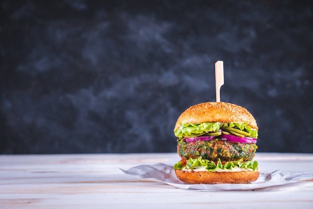Burger végétalien sur une table blanche et un fond bleu foncé