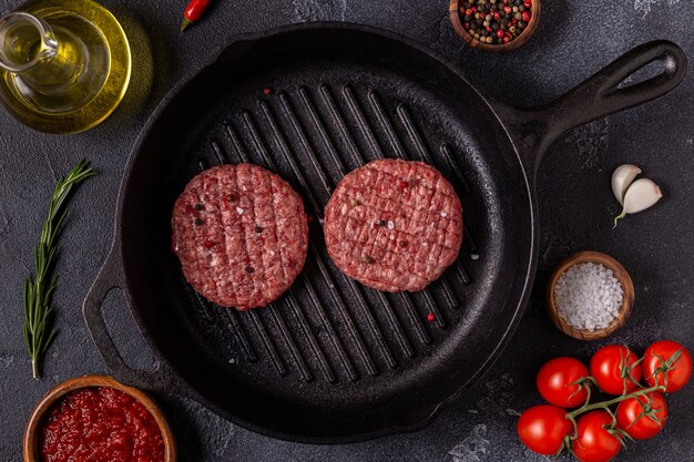 Burgers de boeuf grillés faits maison hachés crus frais dans une poêle à frire, vue de dessus