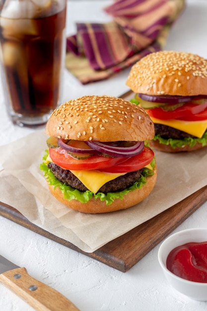 Burgers avec escalope, tomate, laitue, concombre, oignon et fromage. Cuisine américaine. Fast food. Cheeseburger.