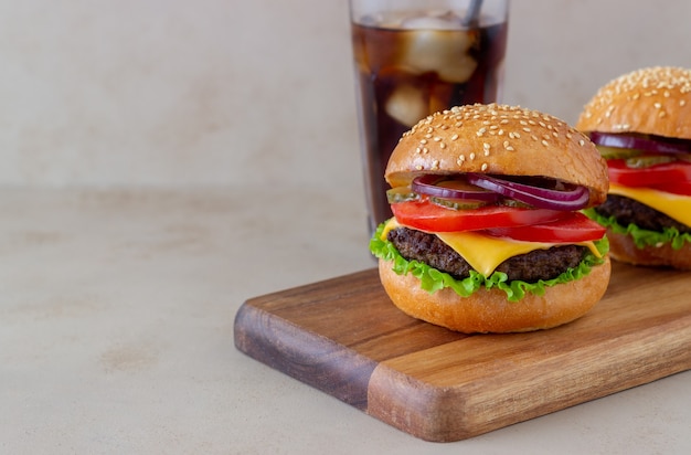 Burgers avec escalope, tomate, laitue, concombre, oignon et fromage. Cuisine américaine. Fast food. Cheeseburger.