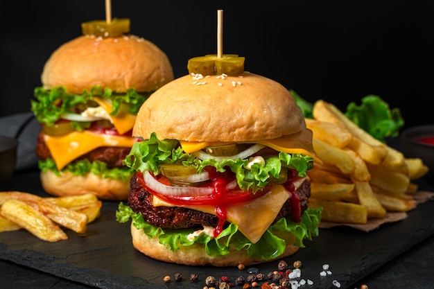 Burgers avec gros plan de galette de boeuf sur fond noir. Fast food. Vue de côté.