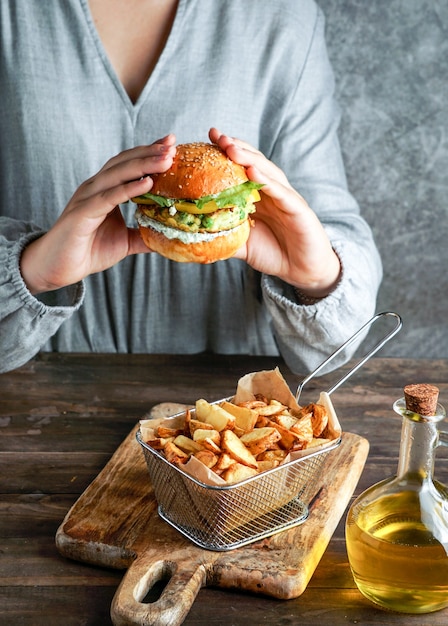 Burgers végétaliens aux lentilles dans les mains de la femme, avec salade et sauce au yaourt sur fond blanc. Concept alimentaire à base de plantes.