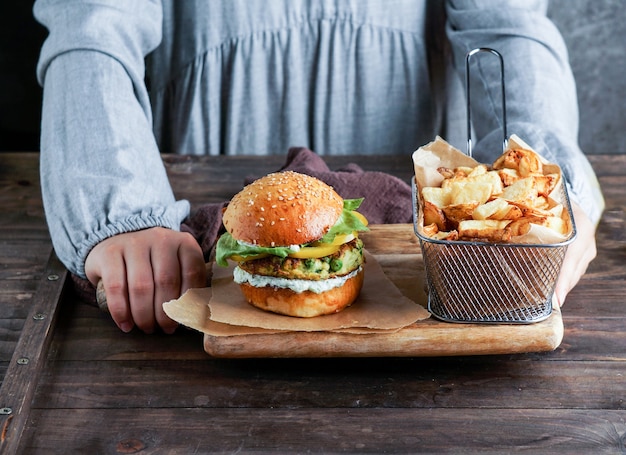 Burgers végétaliens aux lentilles dans les mains de la femme, avec salade et sauce au yaourt sur fond blanc. Concept alimentaire à base de plantes.