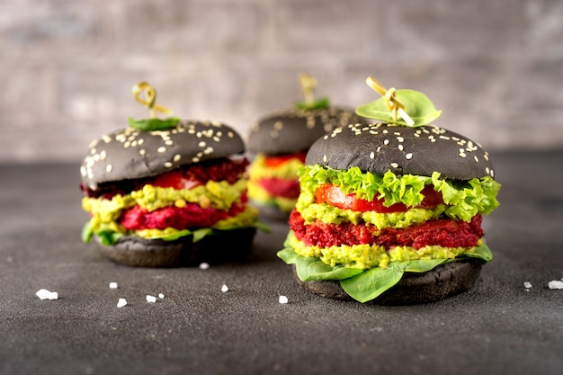 Burgers végétaliens noirs avec des galettes de betterave sur une surface sombre