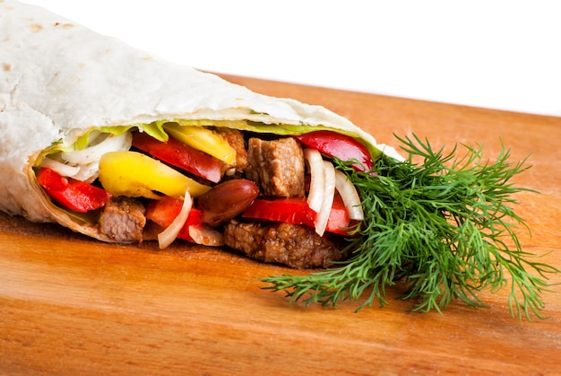 Burrito de boeuf aux poivrons jaunes et rouges, oignon et tomate sur assiette