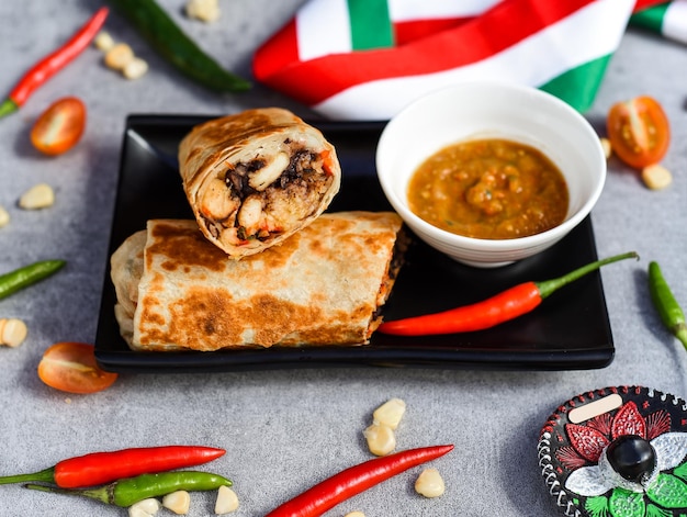 Burrito mexicain au poulet, riz, haricots et fromage servi avec sauce barracha