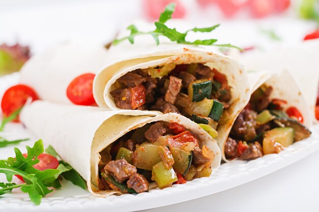 Burritos enveloppe avec du boeuf et des légumes sur un fond clair.