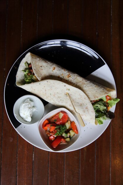 Burritos mexicains sur une assiette avec salade de tomates