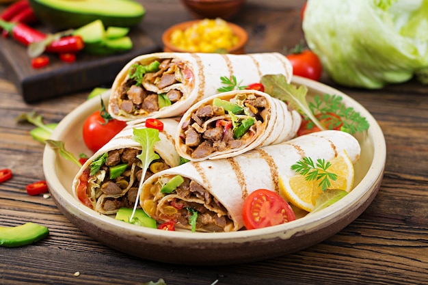 Burritos s&#39;enroule avec du boeuf et des légumes sur un fond en bois. Burrito au bœuf, foo mexicain