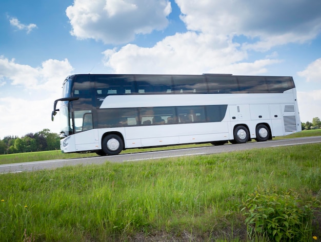 Photo bus à deux étages sur la route par un champ herbeux contre le ciel