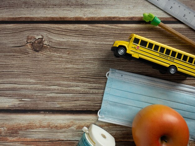 Le bus scolaire et le masque sur table en bois pour l'éducation ou le concept médical