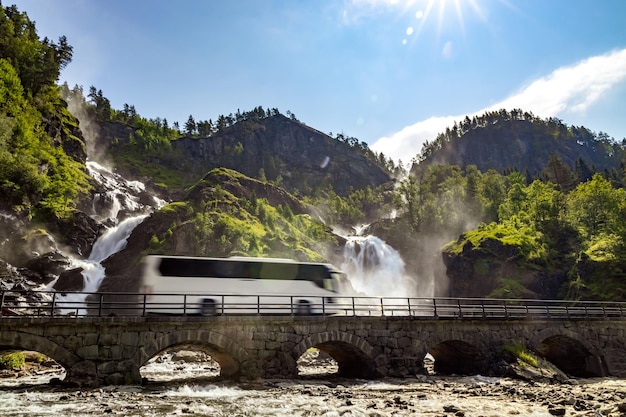 Bus touristique voyageant sur la route Latefossen Waterfall Odda Norvège. Latefoss est une puissante cascade jumelle.