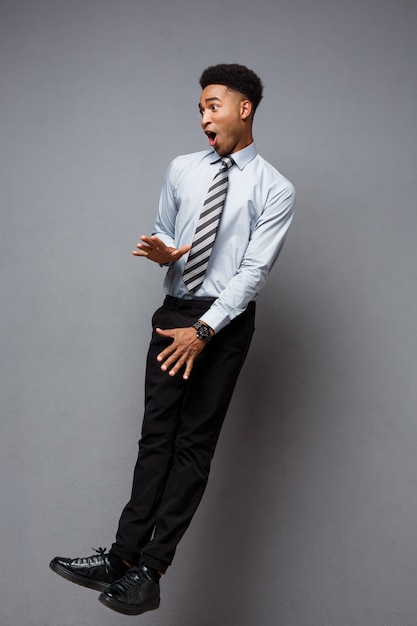 Business Concept - portrait de pleine longueur d&#39;homme d&#39;affaires afro-américain réussie surprenant sauter dans le bureau.