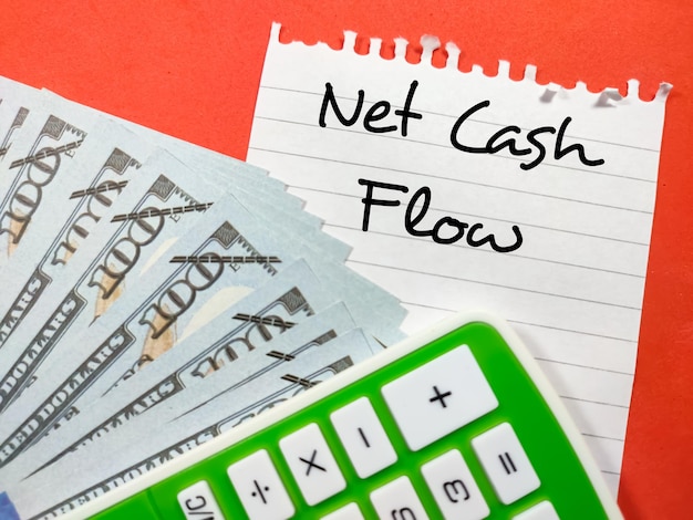 Business conceptText Net Cash Flow écrit sur papier à lettres avec faux argent et calculatrice sur fond rouge