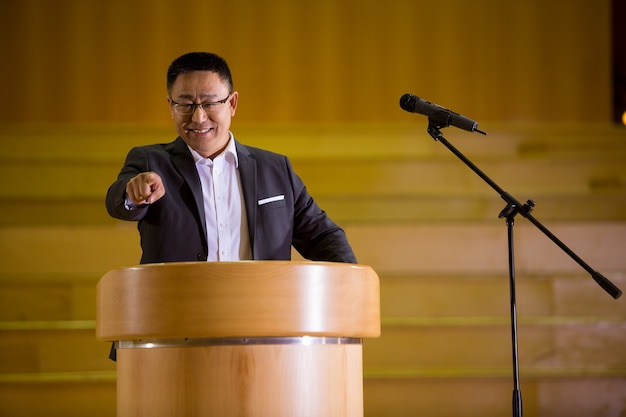 Business executive pointant tout en prononçant un discours au centre de conférence