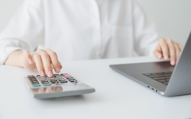 Business woman hand press calculator et calculer les dépenses mensuelles sur la table dans la maison de bureau.