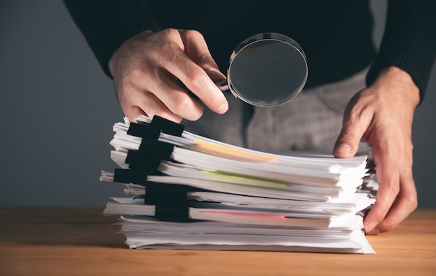 Businessman hand holding document et loupe au bureau