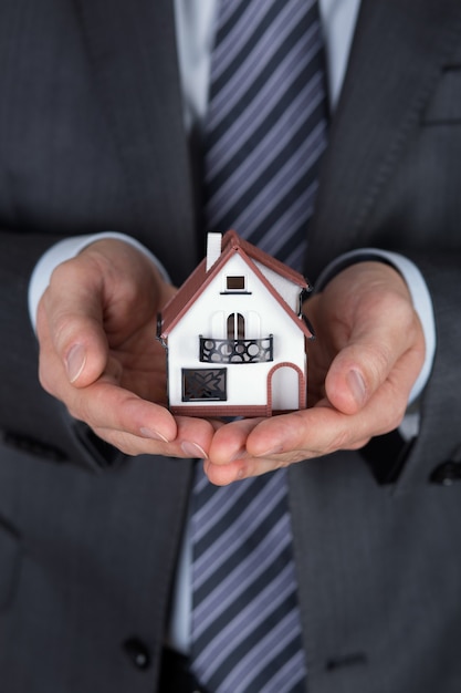 Businessman holding modèle de maison miniature