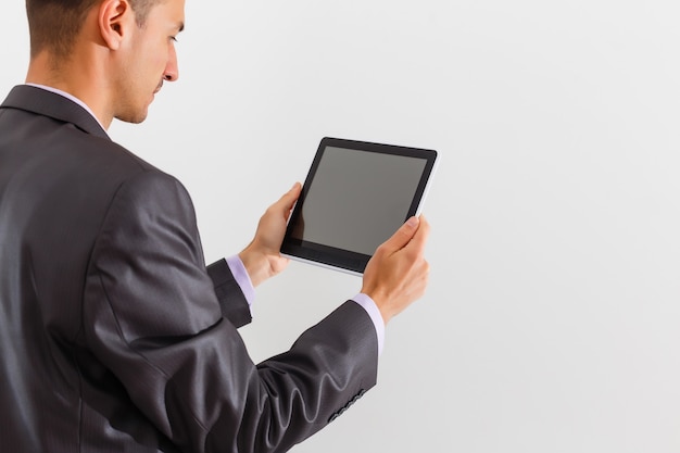 Le businessman holding tablet contre fond blanc